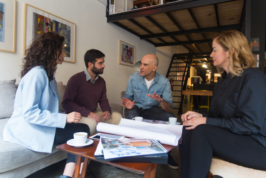 Four professionals discussing plans around a table in an office.